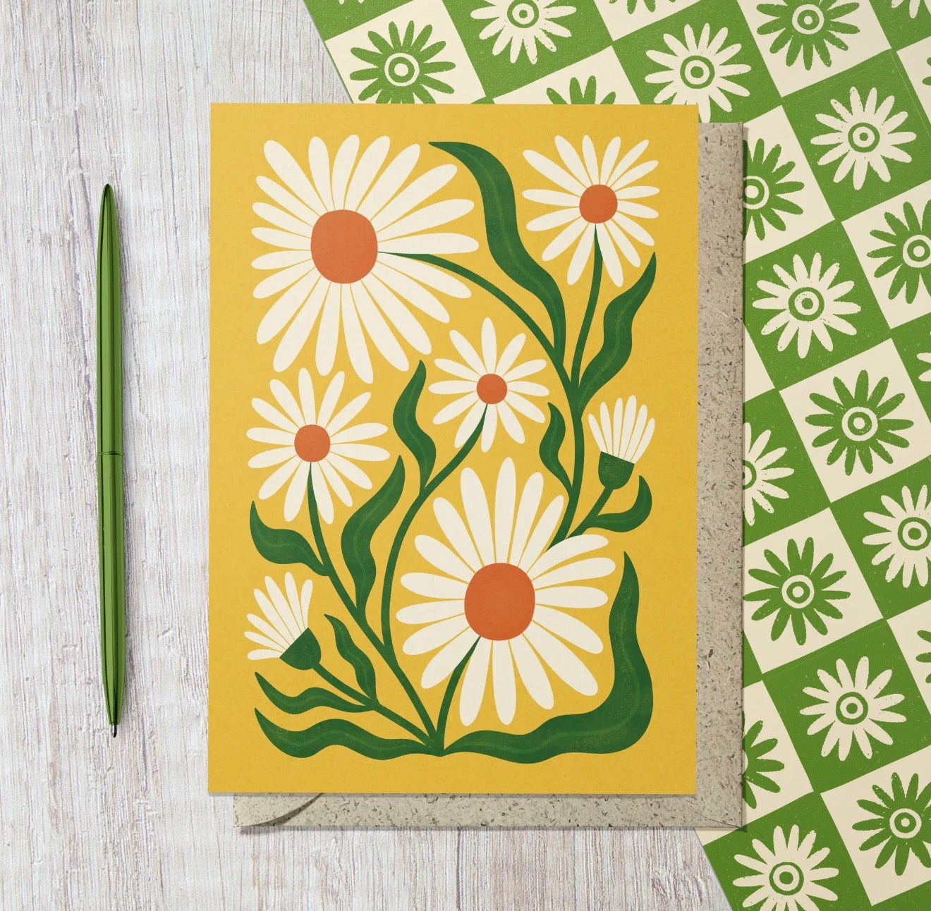Yellow greeting card featuring illustrated white daisies with orange centres and green leaves.