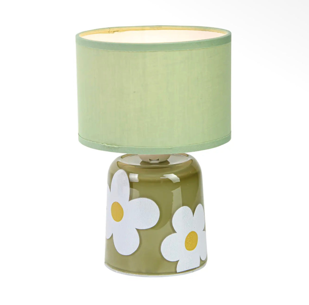 Green table lamp with bold white flower detailing and a simple green fabric shade.