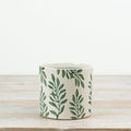 Botanical ceramic planter with green leaf design for indoor plants and home décor.