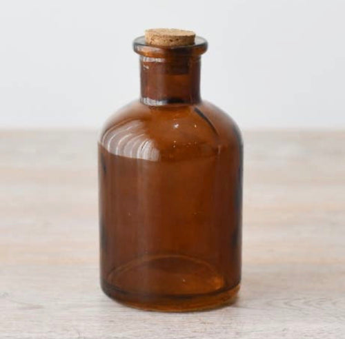 Amber glass bottle with natural cork lid for home décor, shelf styling, storage and dried flowers.