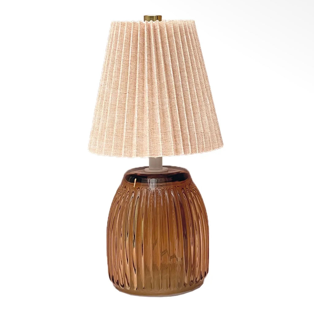 Amber ribbed battery operated LED table lamp with a neutral pleated fabric shade.