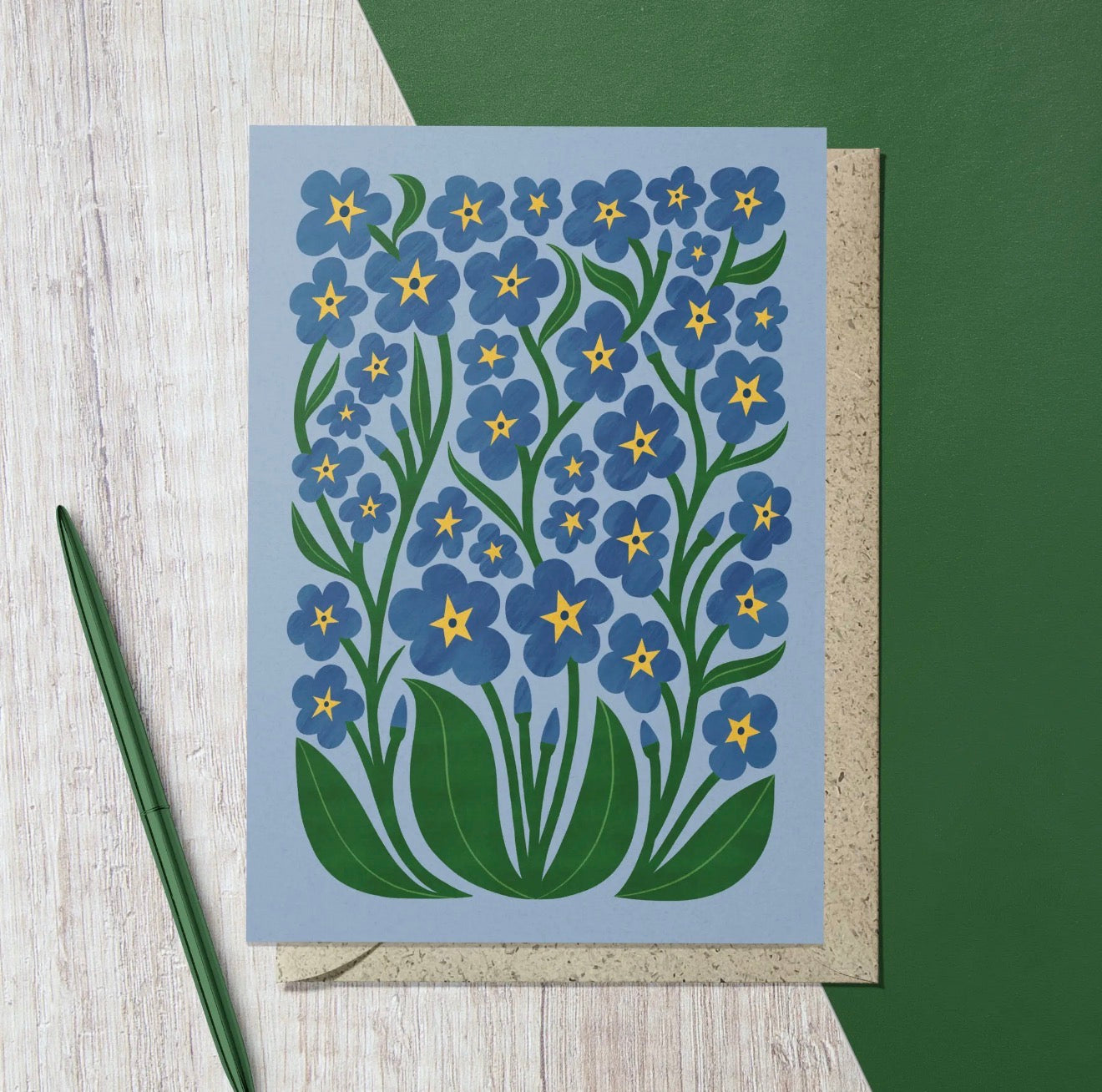 Blue floral greeting card featuring illustrated forget-me-not flowers with green leaves and yellow centres.