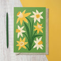 Green greeting card featuring illustrated yellow and cream daffodils with dark green leaves.