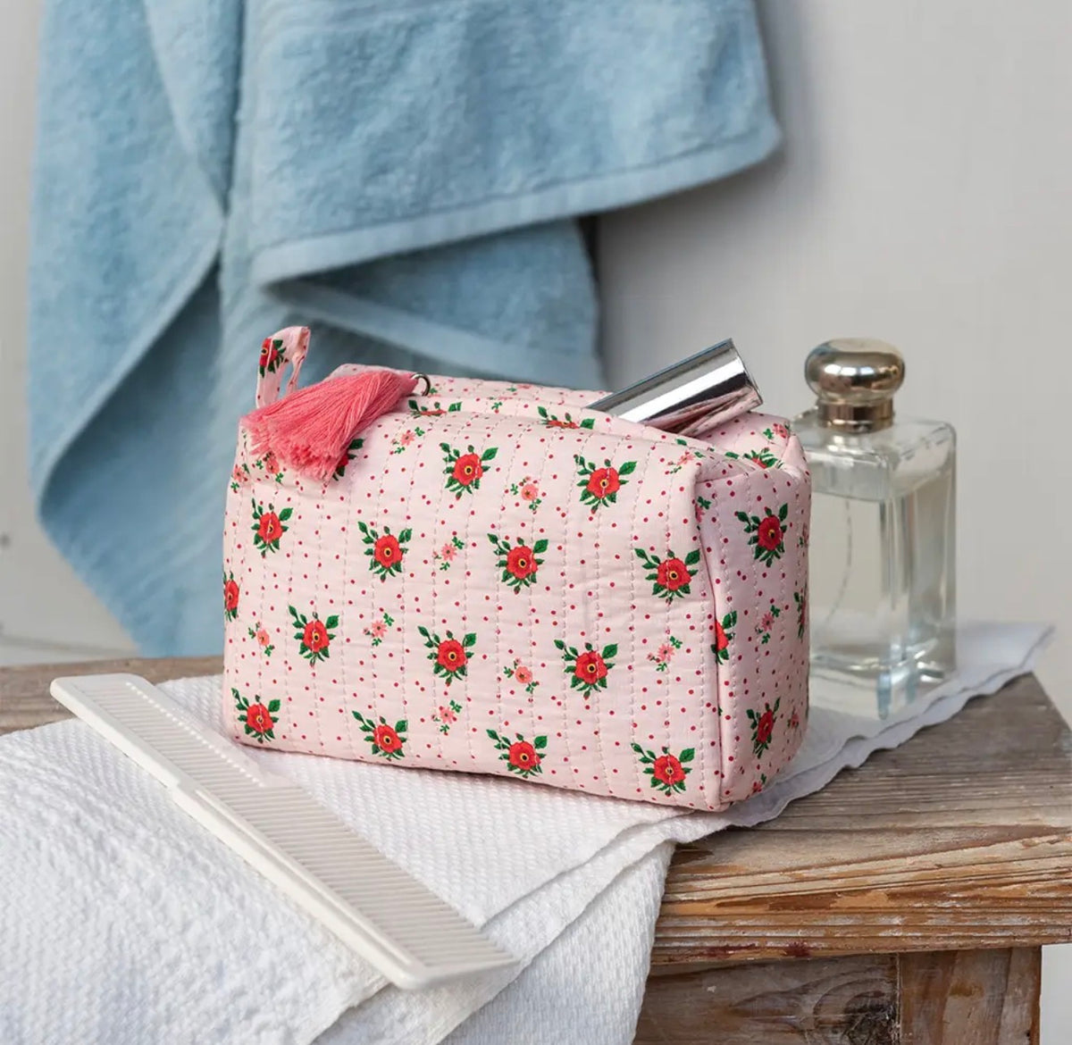 Soft pink quilted makeup bag with a red and green French rose floral print, zip fastening and pink tassel.
