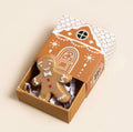 Ceramic gingerbread person keepsake token presented in a festive gingerbread house matchbox.