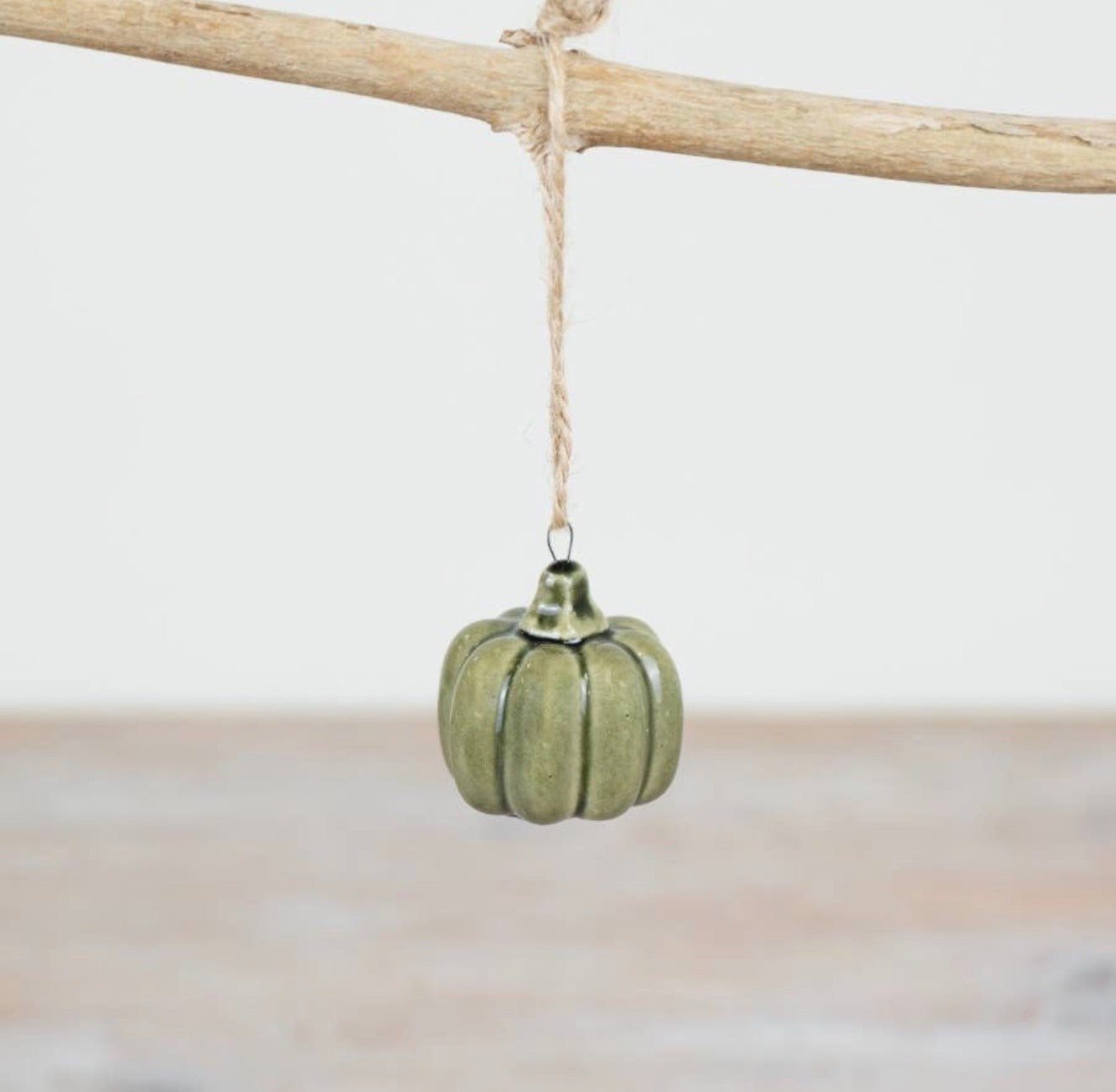 Green ceramic pumpkin hanging ornament with rustic jute string for autumn and seasonal home décor.