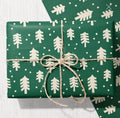 Dark green Christmas wrapping paper featuring a cream tree and snow dot pattern.