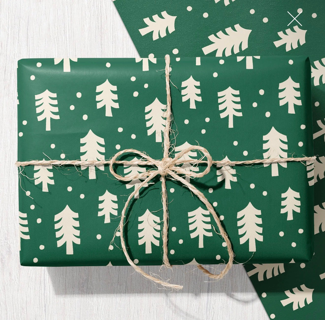 Dark green Christmas wrapping paper featuring a cream tree and snow dot pattern.