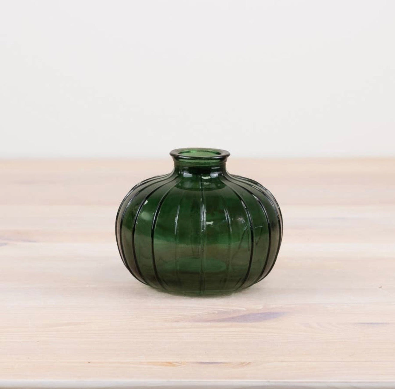 Green ribbed glass bud vase with a rounded shape, perfect for displaying single stems or dried flowers.