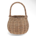 Small natural woven wicker basket with a rounded shape and tall curved carry handle.