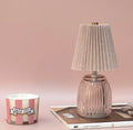 Pink battery operated table lamp styled on books beside a pink striped candle.