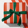 Red and pale pink candy stripe wrapping paper finished with a dark green ribbon bow.