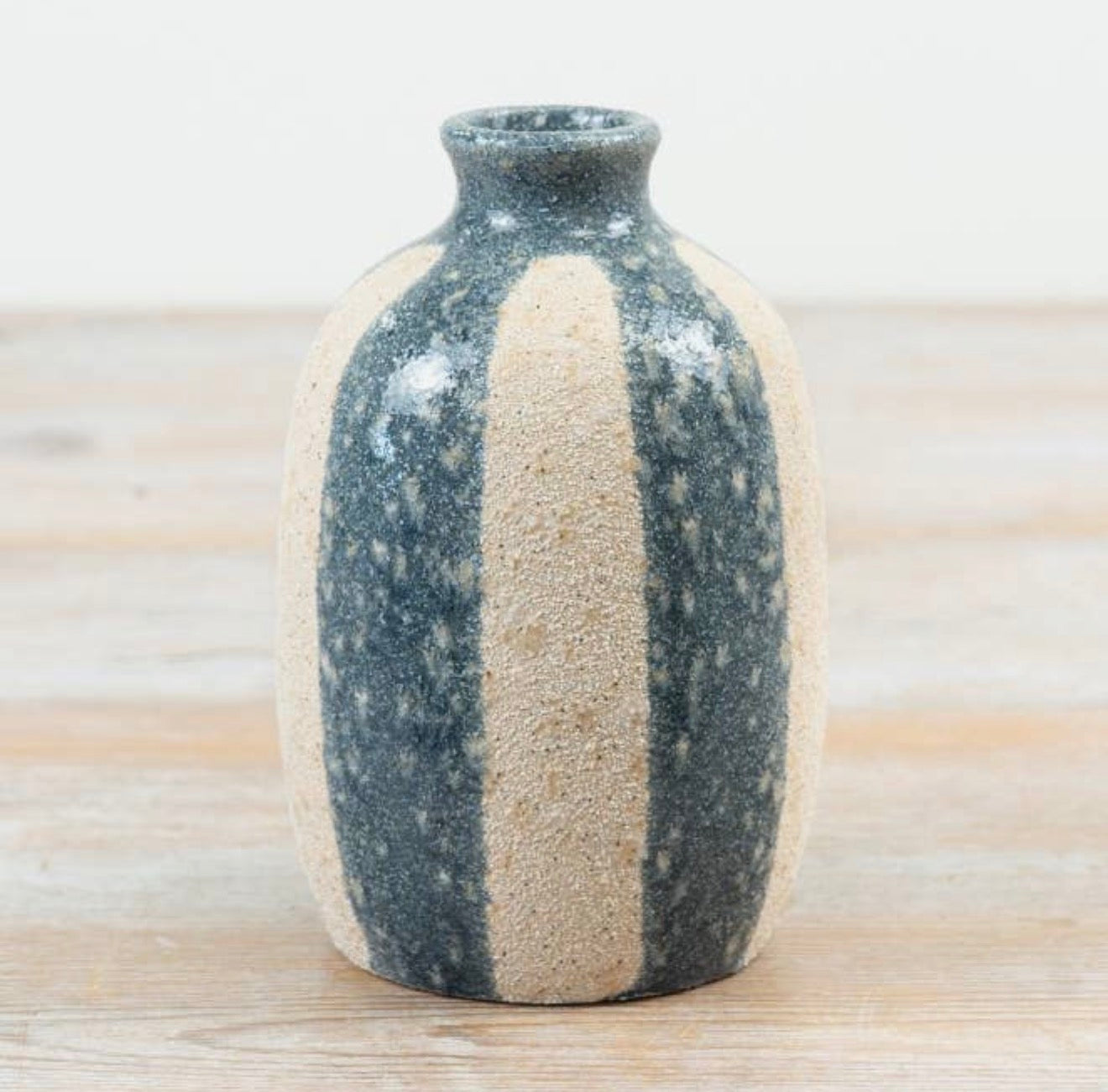 Rustic striped ceramic bud vase with a textured natural stone-effect finish in neutral beige and blue tones.