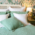 Sage green quilted single bedspread with an intricate stitched pattern styled with coordinating green and white pillows.