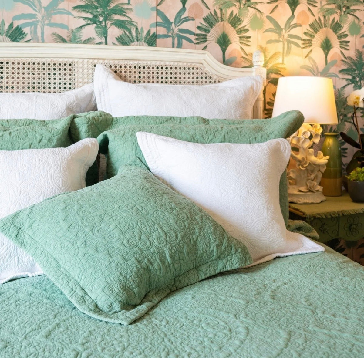 Sage green quilted single bedspread with an intricate stitched pattern styled with coordinating green and white pillows.