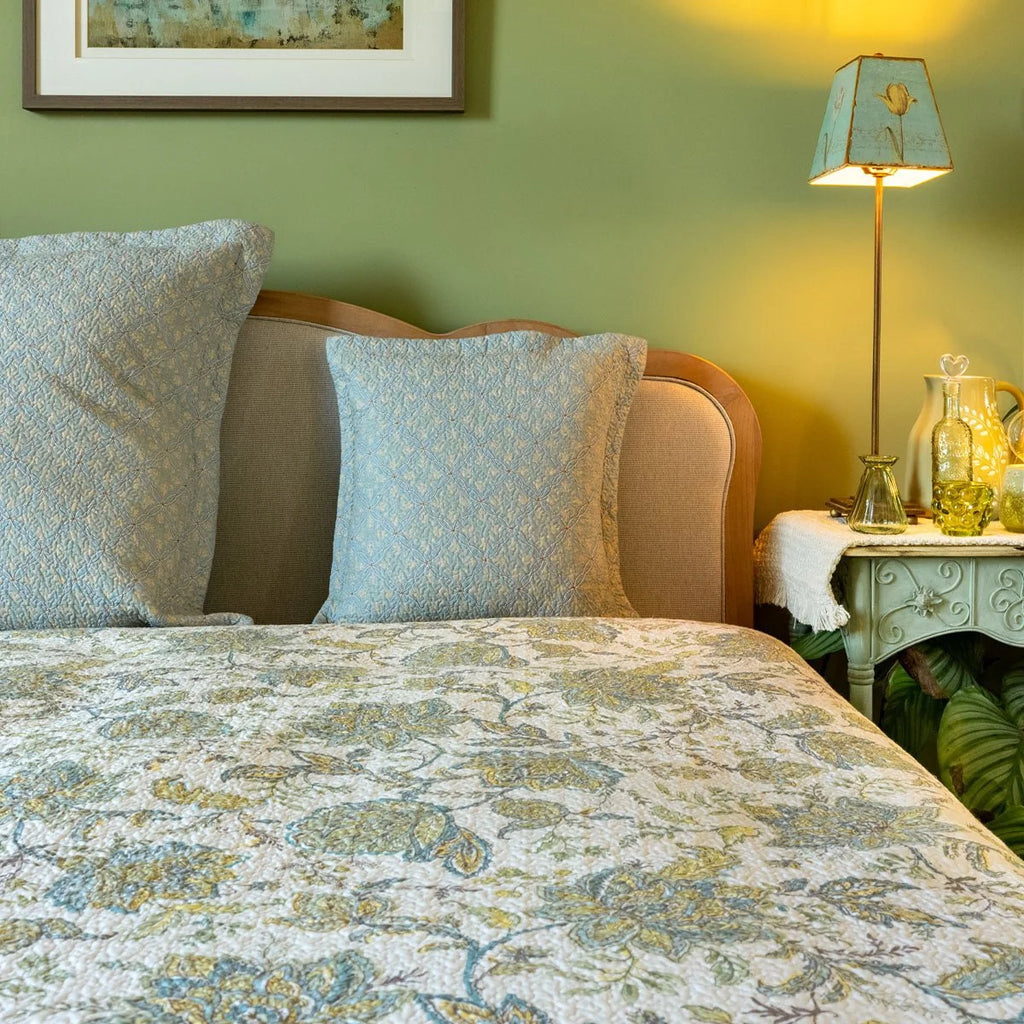 Blue and yellow floral continental pillow sham styled on a bed with coordinating patterned bedding.
