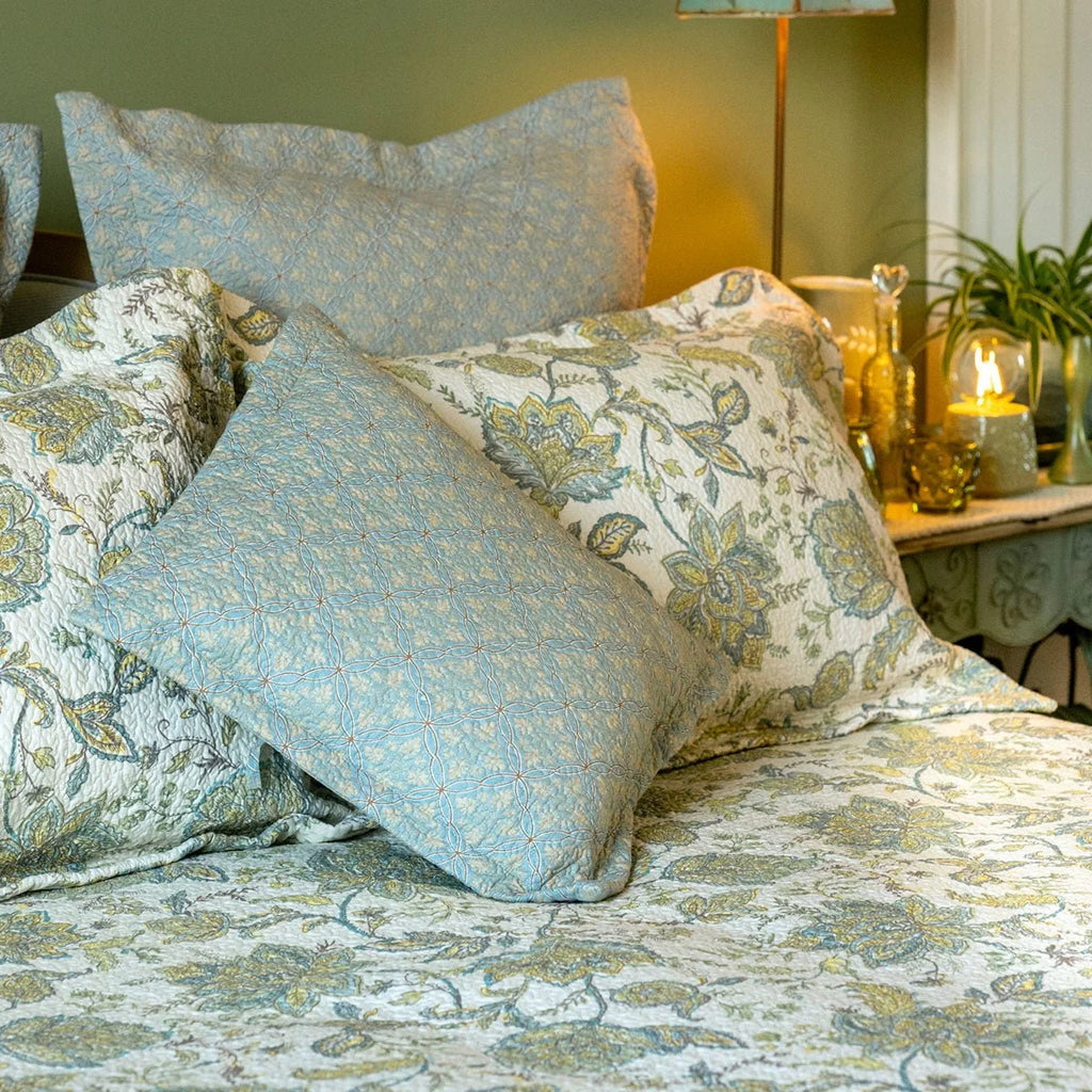 Blue and yellow floral continental pillow sham styled on a bed with coordinating patterned bedding.