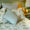 Blue and yellow floral continental pillow sham styled on a bed with coordinating patterned bedding.
