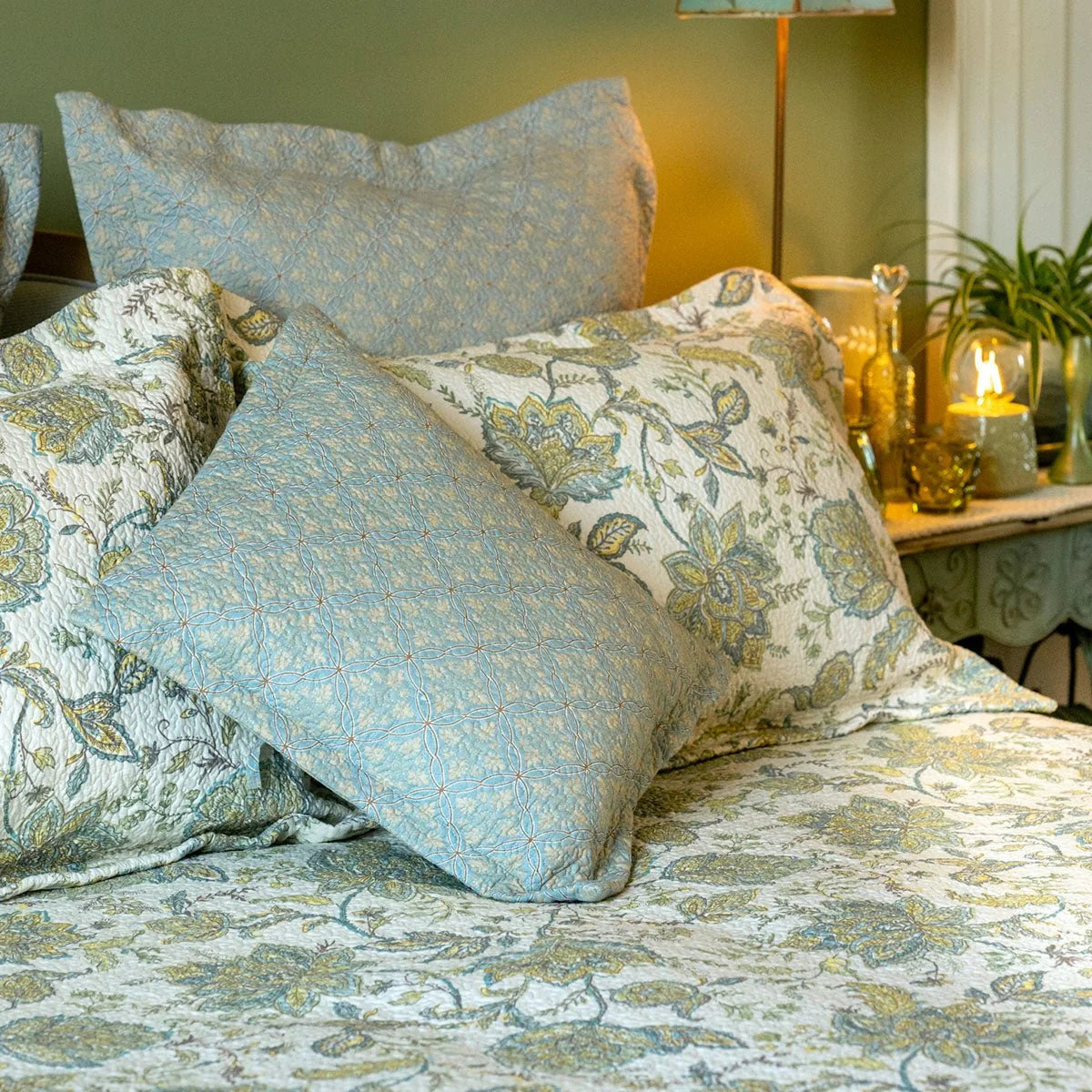Blue and yellow floral continental pillow sham styled on a bed with coordinating patterned bedding.