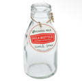 Clear traditional school milk bottle with vintage-style red and green label and twine tag around the neck.